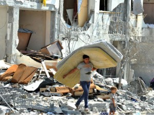 Crianças palestinas procuram por seus objetos, em casas destruídas por ataques israelenses na Faixa de Gaza, em agosto de 2014. Foto: SHAREEF SARHAN/ UN (07/08/2014)